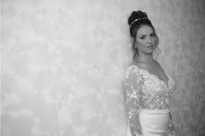 תמונה של כלה נשענת על קיר ומביטה אל המצלמה. התמונה בשחור ולבן