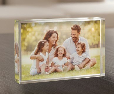 בלוק קריסטל יוקרתי עם הדפסה אישית. הדפסה על בלוק קריסטל יוקרתי בגודל 10x15 ס"מ של הראל צלמים. התמונה מציגה בלוק זכוכית אקרילית עבה ושקופה העומד על שולחן, ובתוכו מודפסת תמונת משפחה מחייכת בטכנולוגיית סובלימציה איכותית. הקריסטל יוצר אפקט תלת-ממדי ועומק לתמונה, פתרון מושלם עבור מתנה עם תמונה אישית או מזכרת מצילומי סטודיו בקריית אתא.